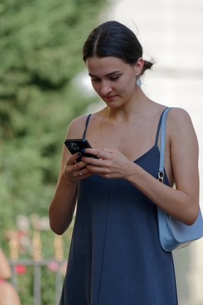 蓝色吊带连衣裙美女低头看手机图片